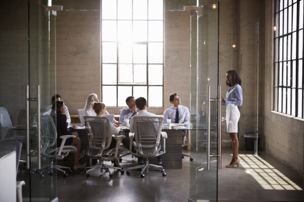 Team gathered in a modern glass-walled conference room, reflecting The William Stanley CFO Group’s analysis on the Farfetch–Richemont transaction featured in Glossy.