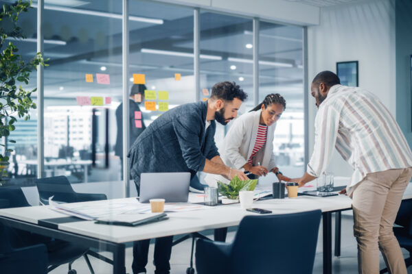 Diverse professionals collaborating around a conference table with post-it notes in the background, illustrating The William Stanley CFO Group’s Teamhood feature on cross-functional team strategies.