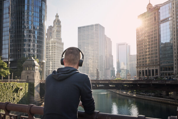 Man wearing headphones overlooking city skyline while listening to a business podcast—Talk Nerdy to Me, hosted by The William Stanley CFO Group