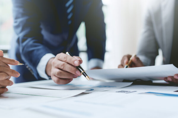 Close-up of professionals reviewing financial documents and contracts, representing The William Stanley CFO Group’s Business Insider feature on student loan deferment strategies.
