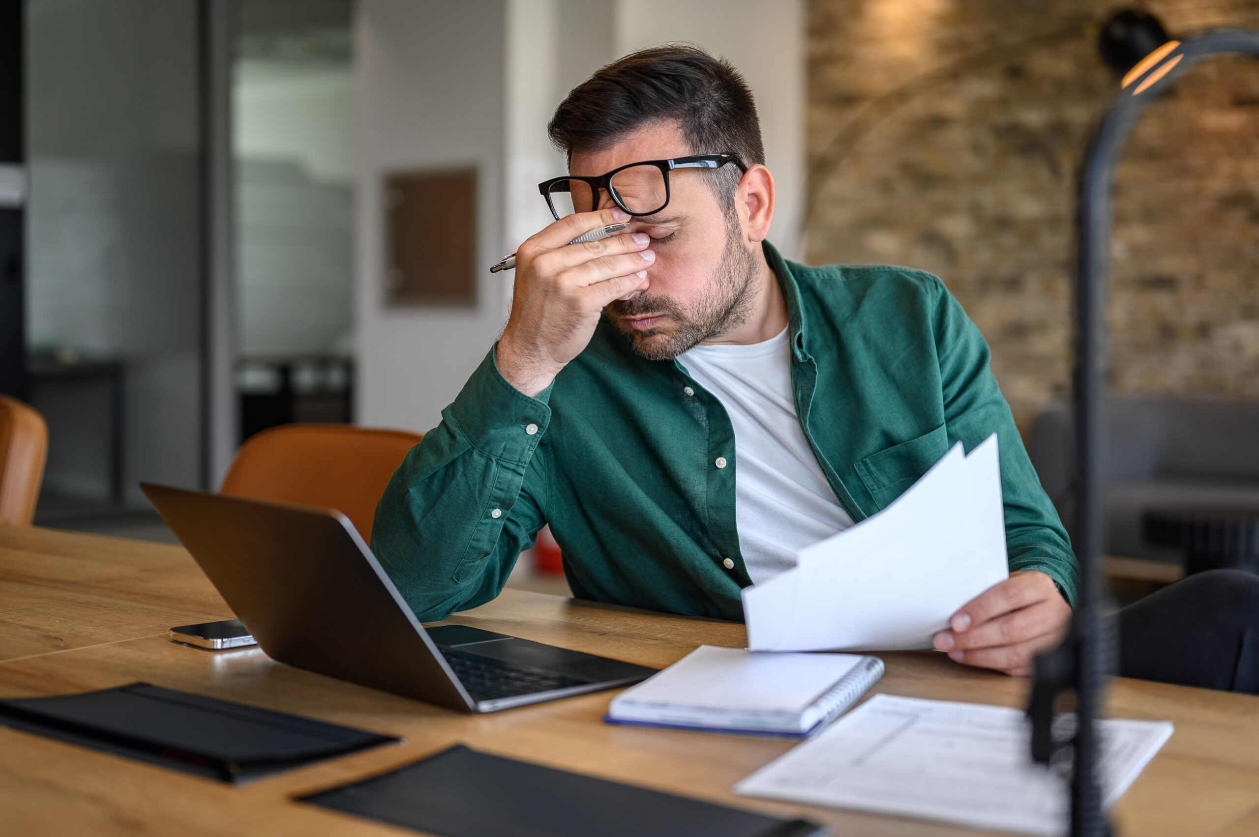 Concerned man reviewing documents at his desk, symbolizing The William Stanley CFO Group’s Best Products feature on how to cancel a credit card responsibly.