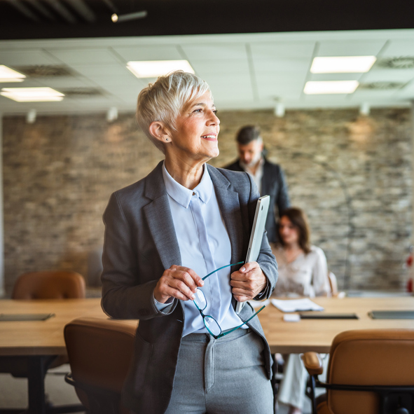 businesswoman hold laptop in arms and smile at workplace